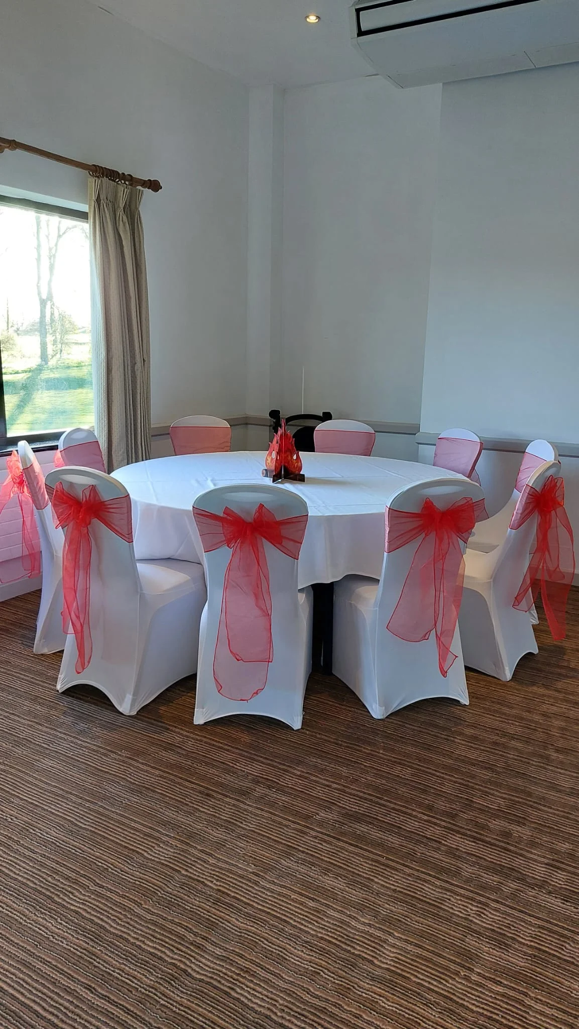 Venue Table Setup with White Chairs and Red Sashes